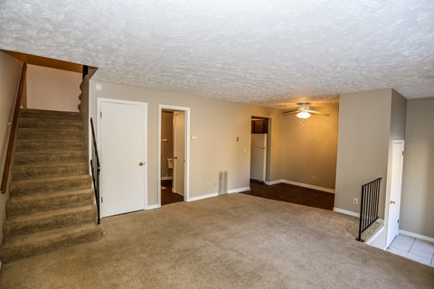 a living room with a staircase and a carpeted floor