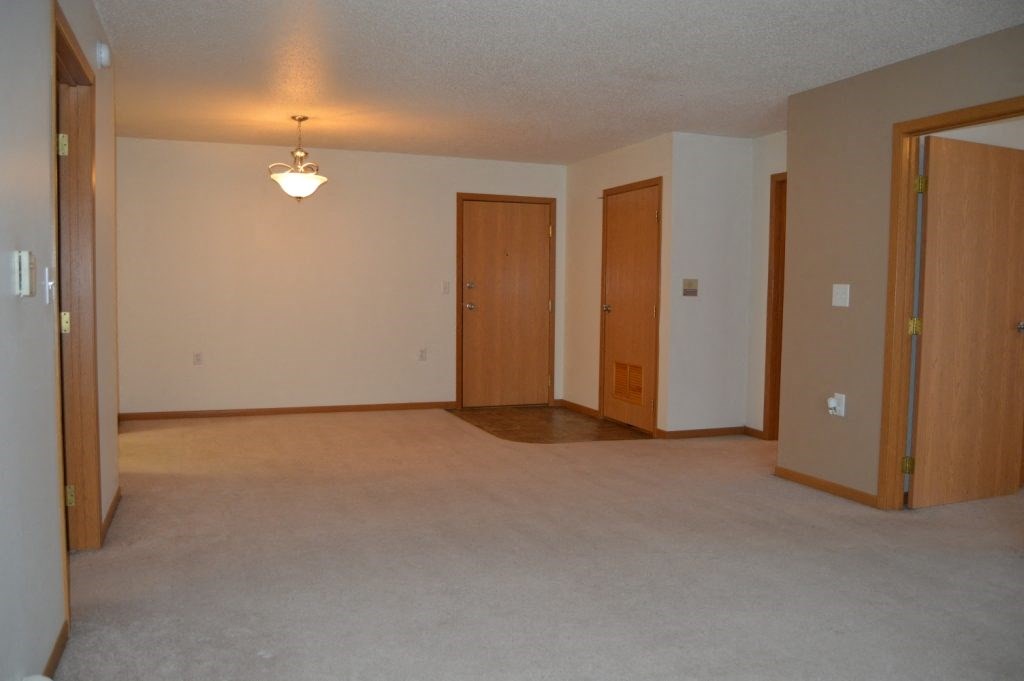 an empty living room with three doors and a lamp