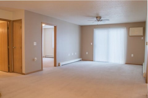 an empty living room with a ceiling fan and a closet.  Fargo, ND Summit Point Apartments