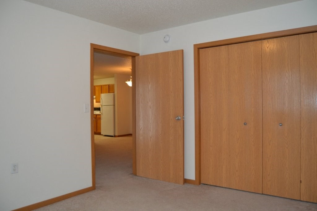 a bedroom with a closet and a kitchen in the background
