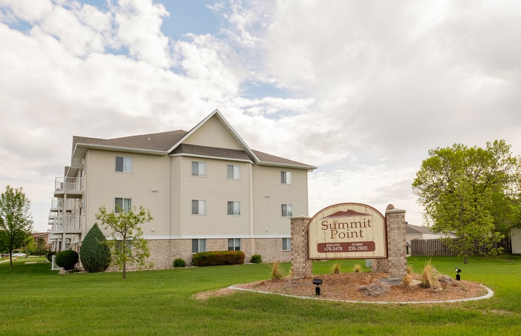 a three story apartment building with a sign out front. Fargo, ND Summit Point Apartments