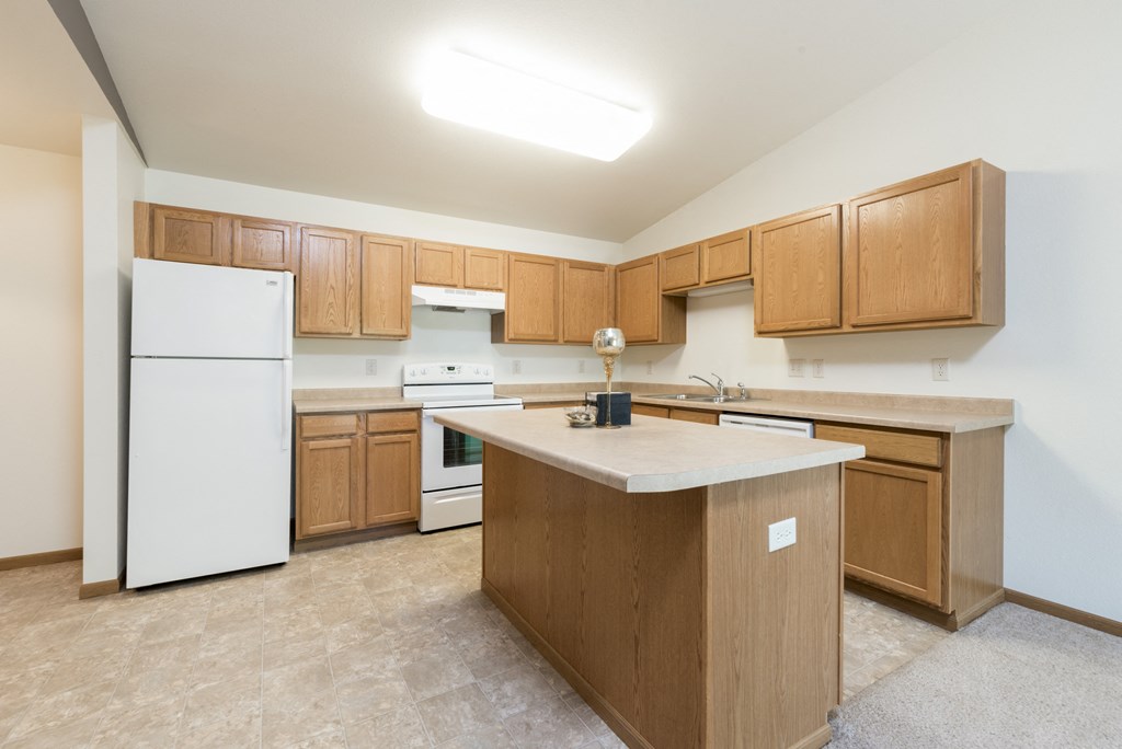 Large kitchen with white appliances and wooden cabinets at Sunset Ridge Apartments in Bismarck