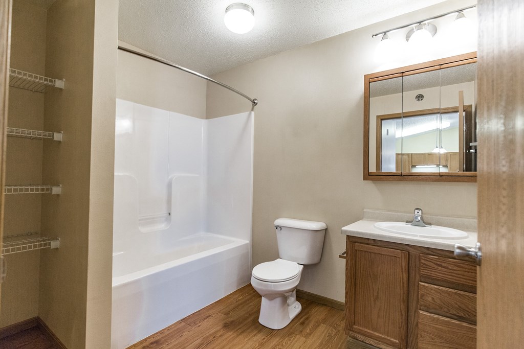 Bathroom with a shower toilet sink and mirror at Sunset Ridge Apartments in Bismarck, 58503 ND