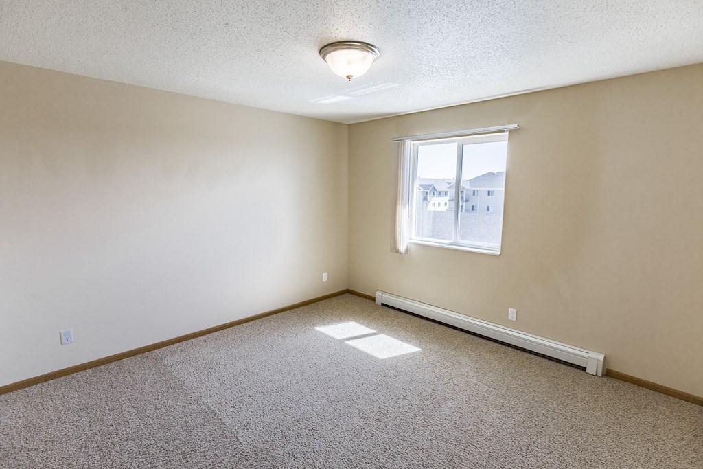 Living room of an empty home with a window at Sunset Ridge Apartments in Bismarck, ND