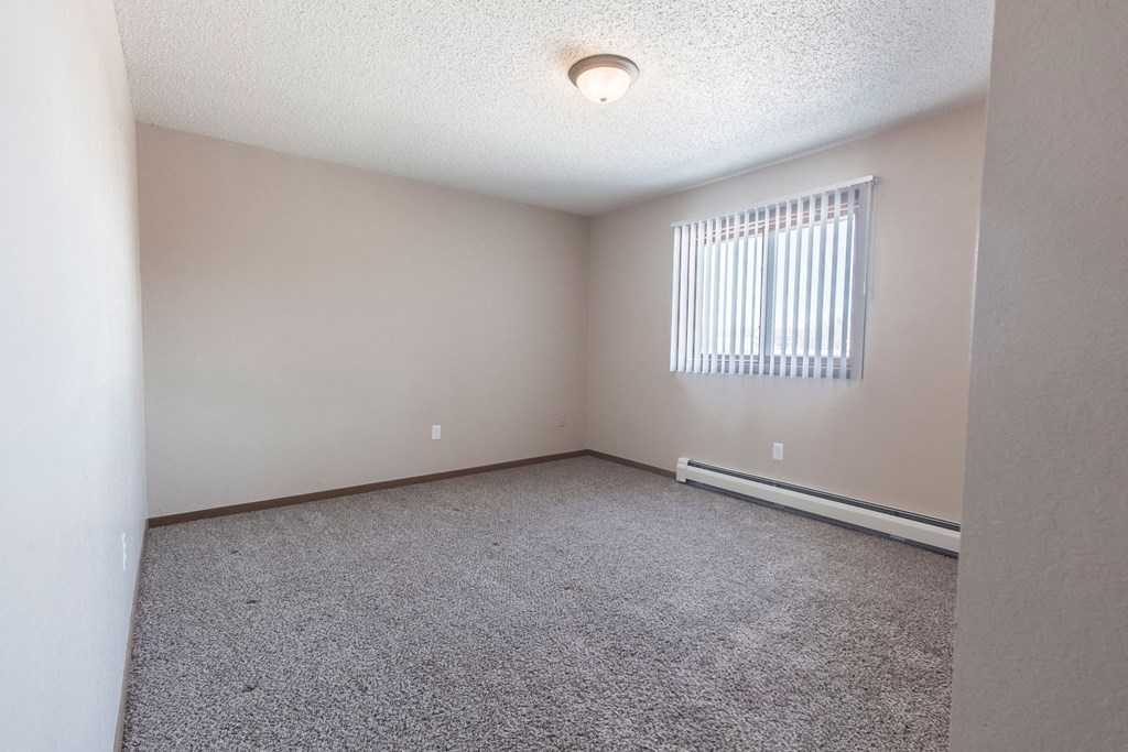 Grand Forks, ND Sunview apartments. a bedroom with a large window and beige carpet