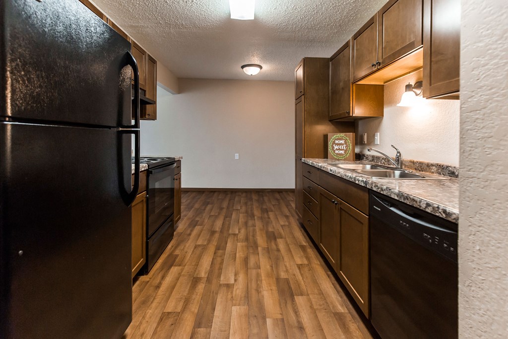 Grand Forks, ND Sunview apartments. a kitchen with a black refrigerator freezer next to a black stove top oven