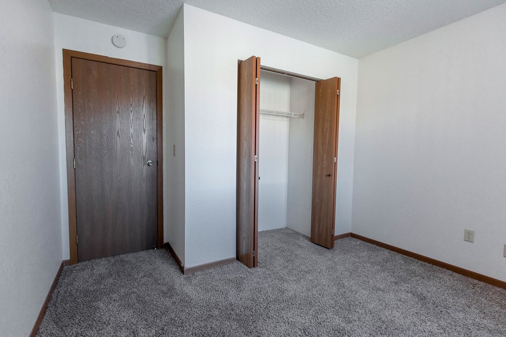 Grand Forks, ND Sunview apartments. an empty bedroom with a closet and a carpeted floor