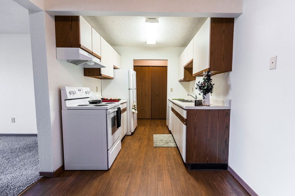 Grand Forks, ND Sunview apartments. a kitchen with white appliances and wooden cabinets