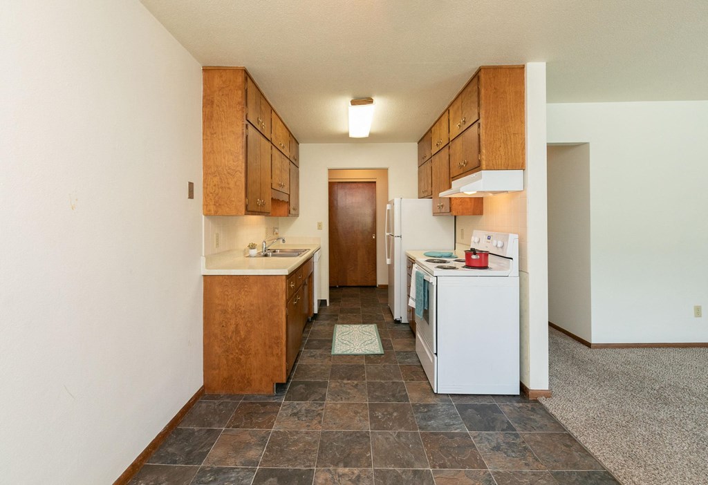 a kitchen with white appliances and wooden cabinets. Fargo, ND Islander Apartments