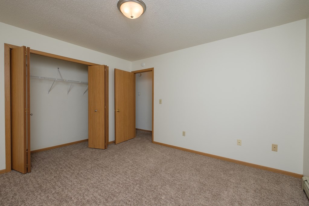 an empty room with two doors and a closet. Fargo, ND Twin Parks Apartments.