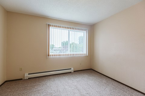 Grand Forks, ND Twin Drive Apartments. A bedroom with a window and a carpeted floor