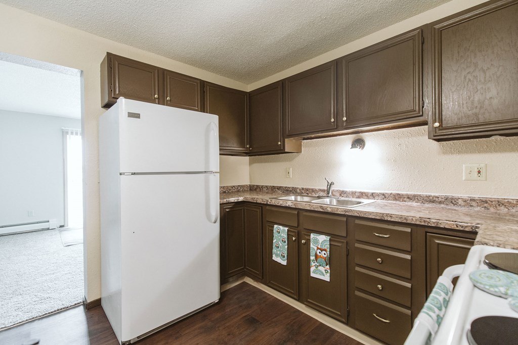 Grand Forks, ND Twin Drive Apartments. A kitchen with white appliances and dark cabinets