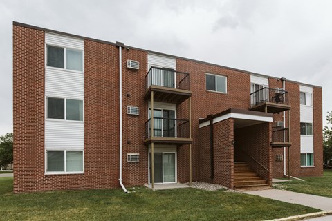 the exterior of a brick apartment building with stairs and grass