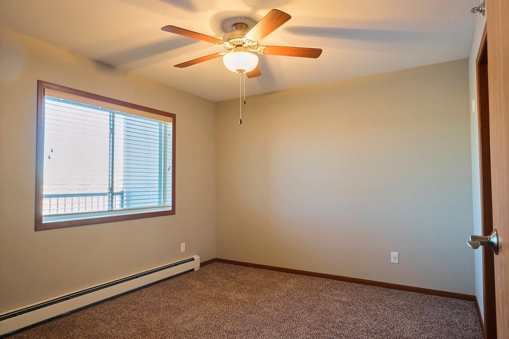 an empty bedroom with a ceiling fan and a window. Fargo, ND Urban Plains Apartments