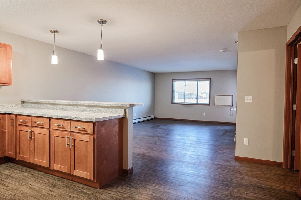 an empty living room and kitchen with wood floors and a counter top. Fargo, ND Urban Plains Apartments