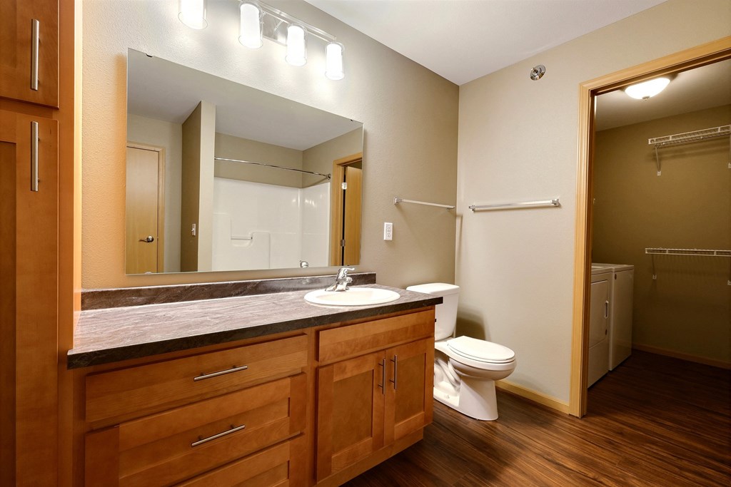 a bathroom with a toilet and a sink and a mirror. Fargo, ND Urban Plains Apartments