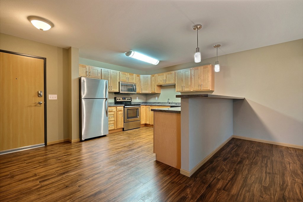 a kitchen with wood flooring and a stainless steel refrigerator. Fargo, ND Urban Plains Apartments