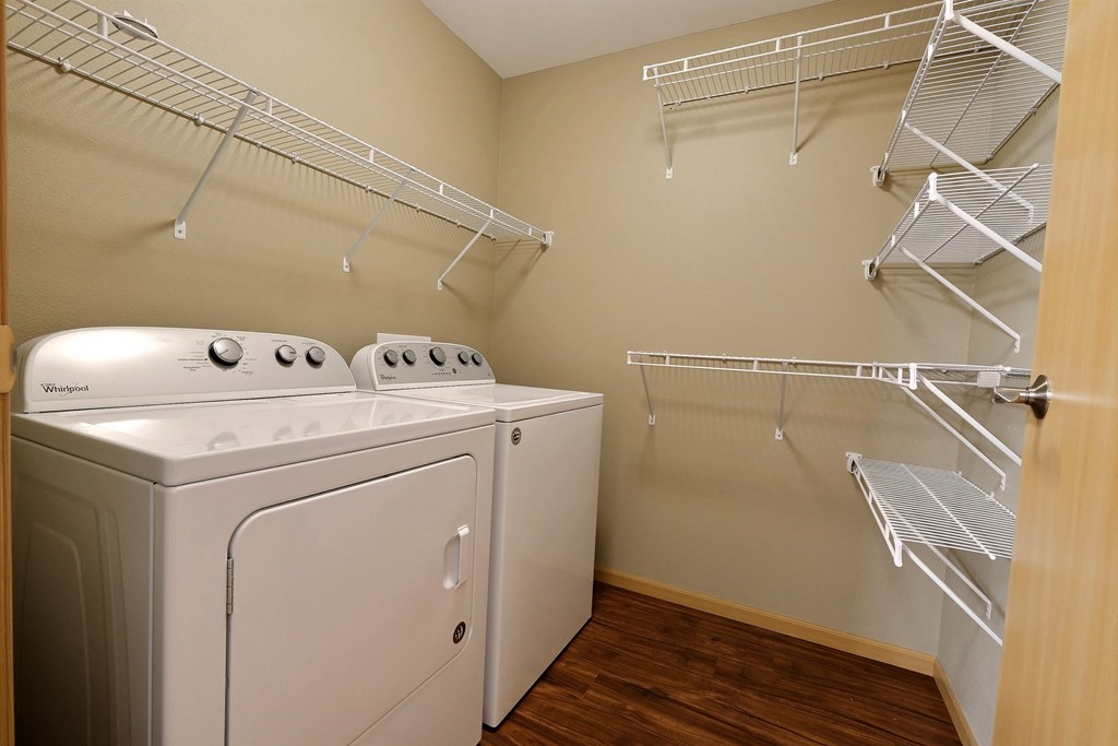a spacious laundry room with a washer and dryer and a closet with shelves. Fargo, ND Urban Plains Apartments