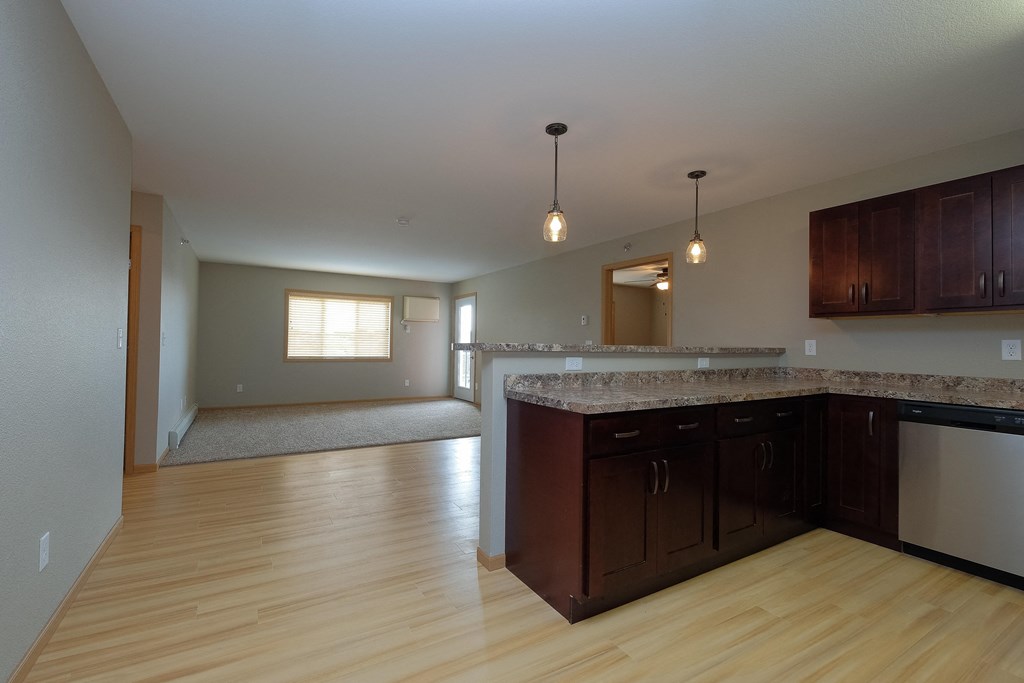 an empty kitchen and living room with wood flooring. Fargo, ND Urban Plains Apartments