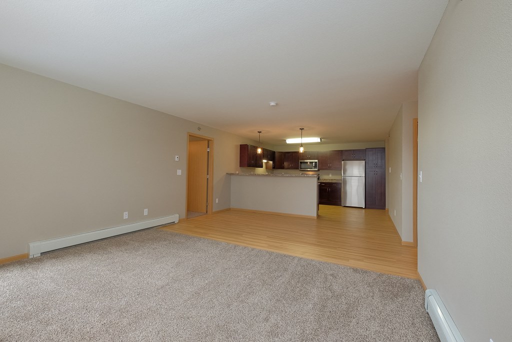 an empty living room and kitchen with a hard wood floor. Fargo, ND Urban Plains Apartments