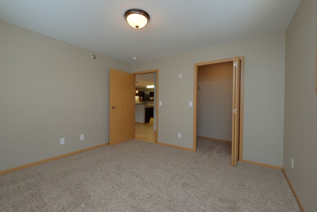 a bedroom with a door to a bedroom and a closet. Fargo, ND Urban Plains Apartments