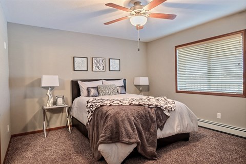 a bedroom with a large bed and a ceiling fan. Fargo, ND Urban Plains Apartments