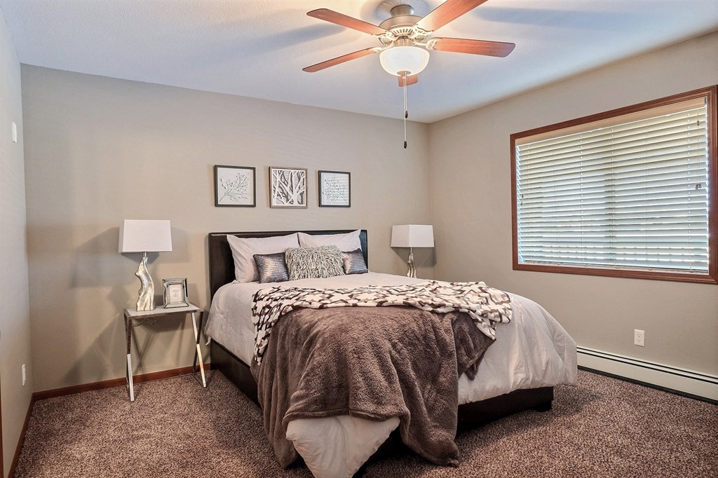 Fargo, ND Urban Plains Apartments | Bedroom a bedroom with a large bed and a ceiling fan. Fargo, ND Urban Plains Apartments