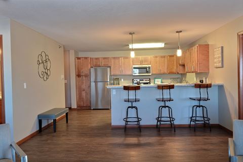 an empty living room with a kitchen with a bar and stools. Fargo, ND Urban Plains Apartments