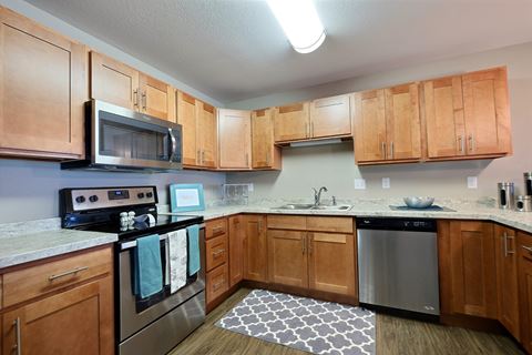an empty kitchen with wooden cabinets and stainless steel appliances. Fargo, ND Urban Plains Apartments