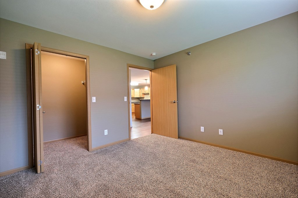 a bedroom with a closet and a door to a bathroom. Fargo, ND Urban Plains Apartments