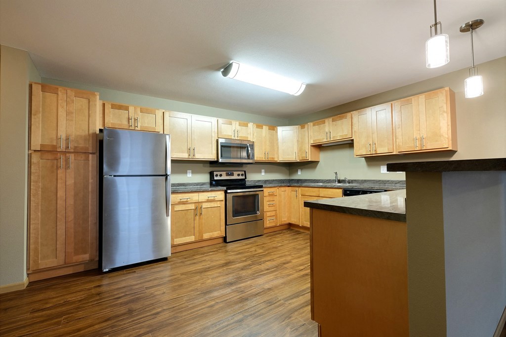 a kitchen with wooden cabinets and stainless steel appliances. Fargo, ND Urban Plains Apartments