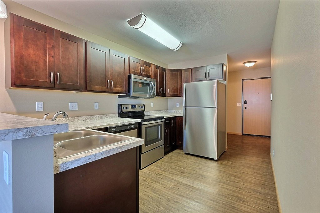 a kitchen with stainless steel appliances and wooden cabinets. Fargo, ND Urban Plains Apartments