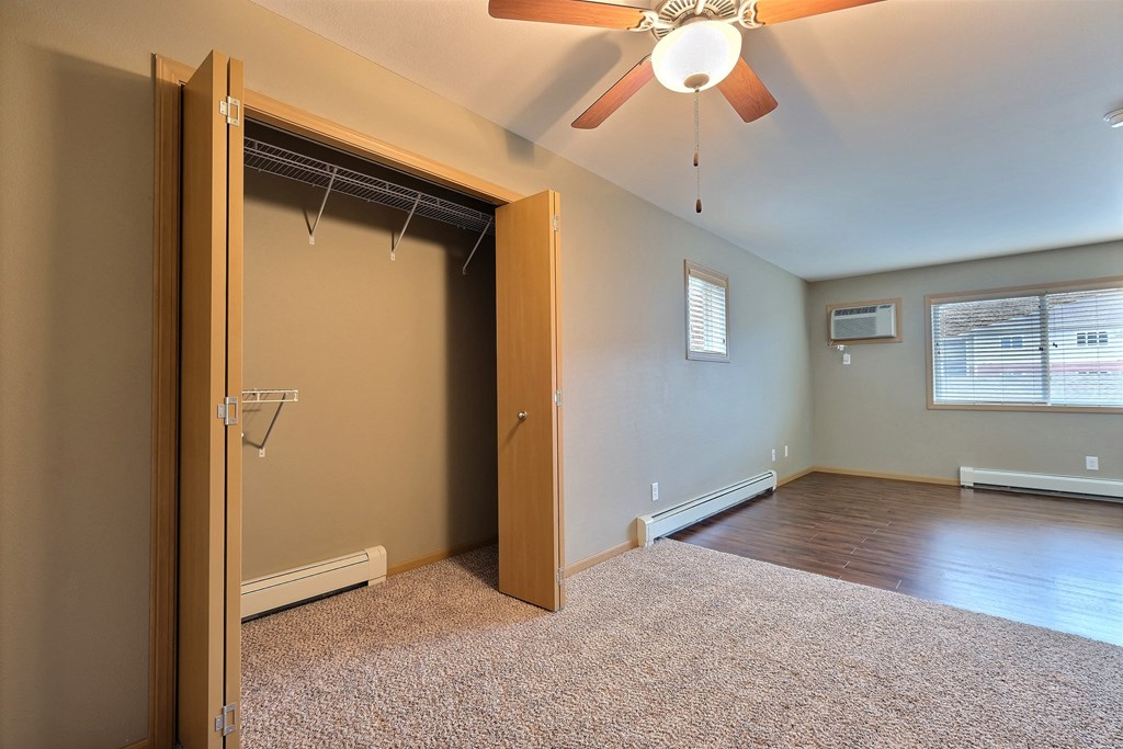 an empty room with a closet and a ceiling fan. Fargo, ND Urban Plains Apartments
