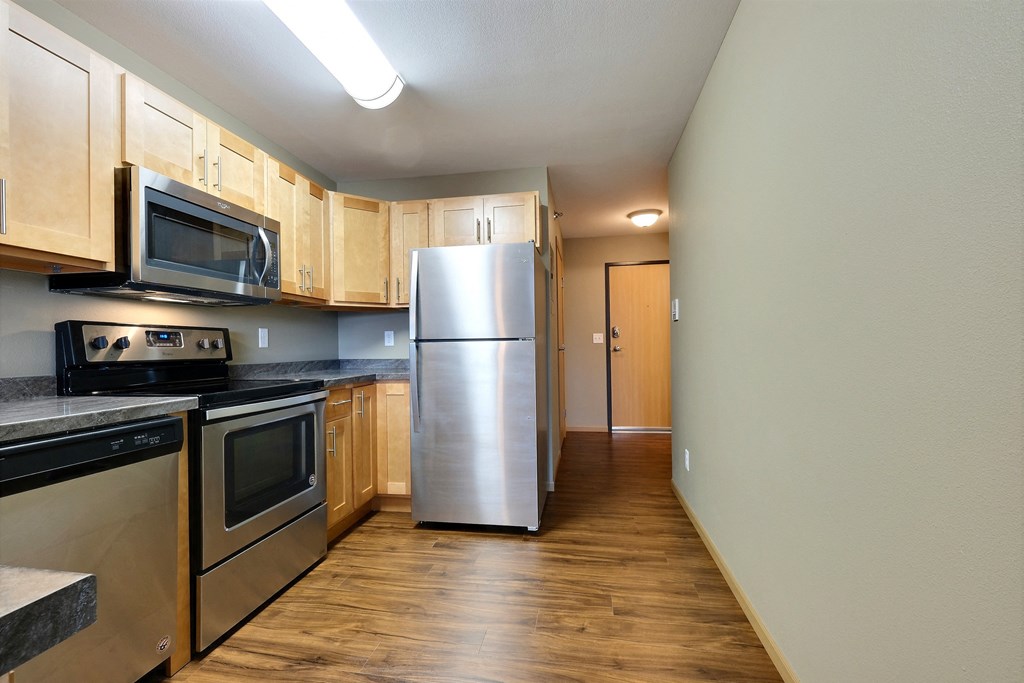 an empty kitchen with stainless steel appliances and wooden cabinets. Fargo, ND Urban Plains Apartments