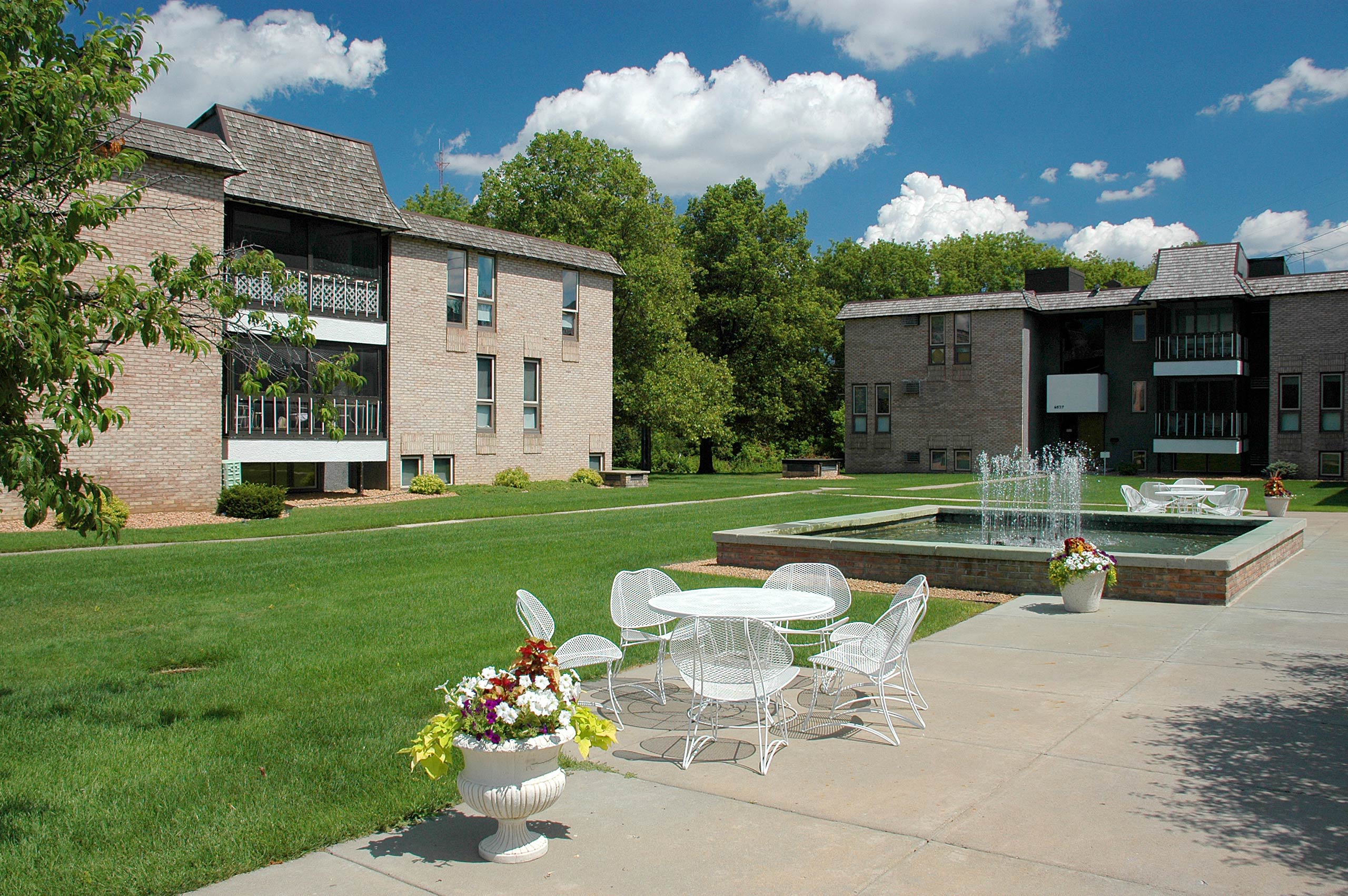 Golden Valley, MN Valley View Apartments. a courtyard with tables and chairs and a fountain