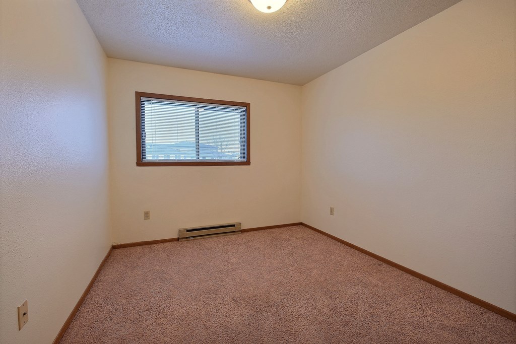 the living room of an empty house with a window. Fargo, ND Village West Apartments