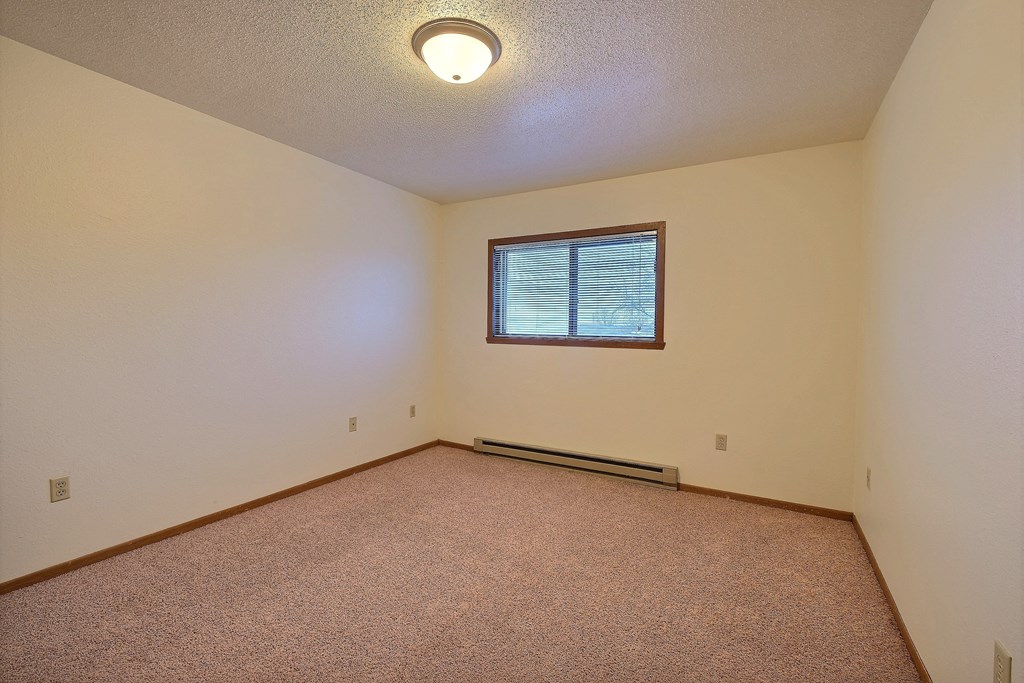 the living room of an empty house with a window. Fargo, ND Village West Apartments