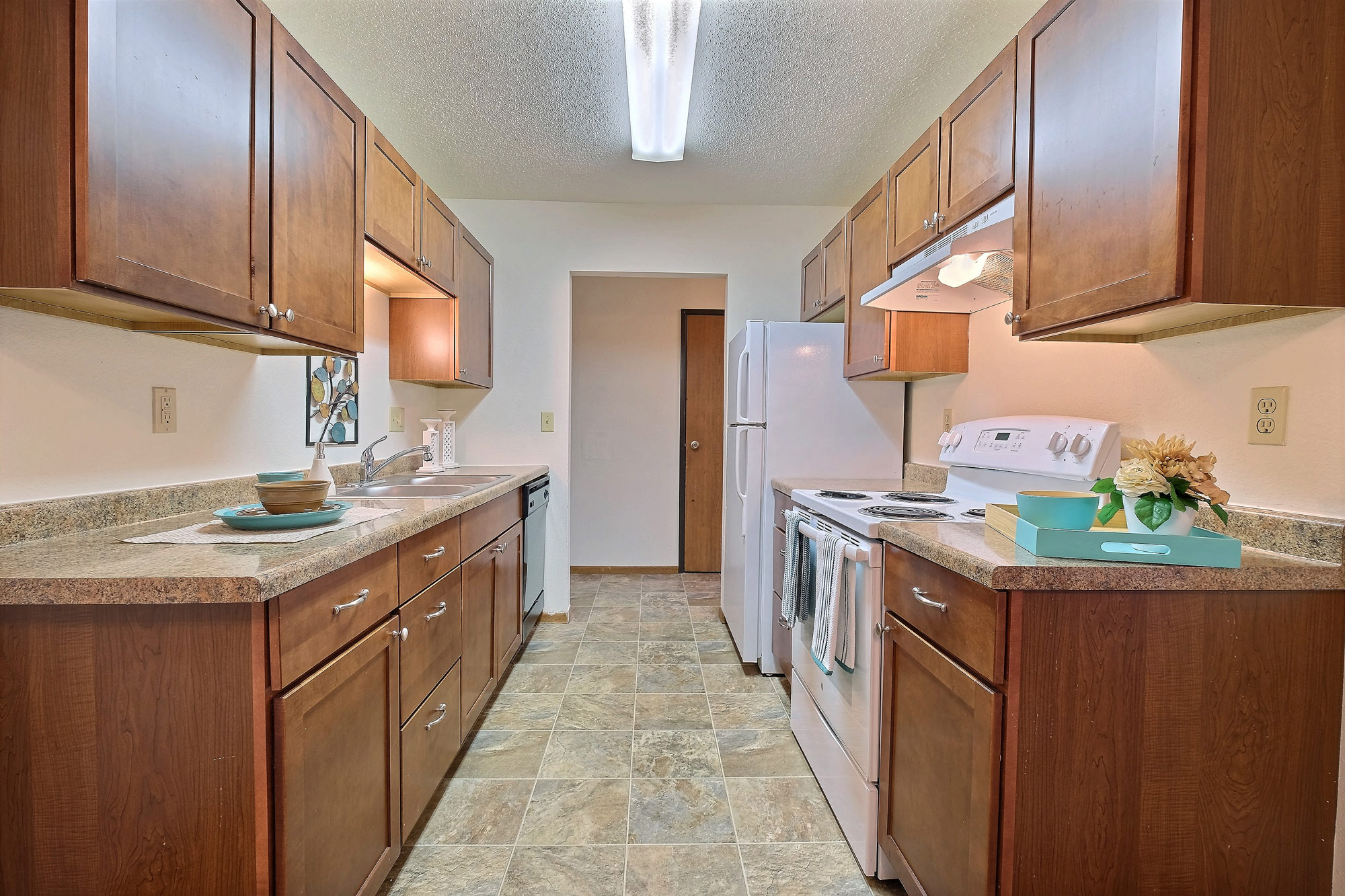 a kitchen with white appliances and wooden cabinets. Fargo, ND Village West Apartments