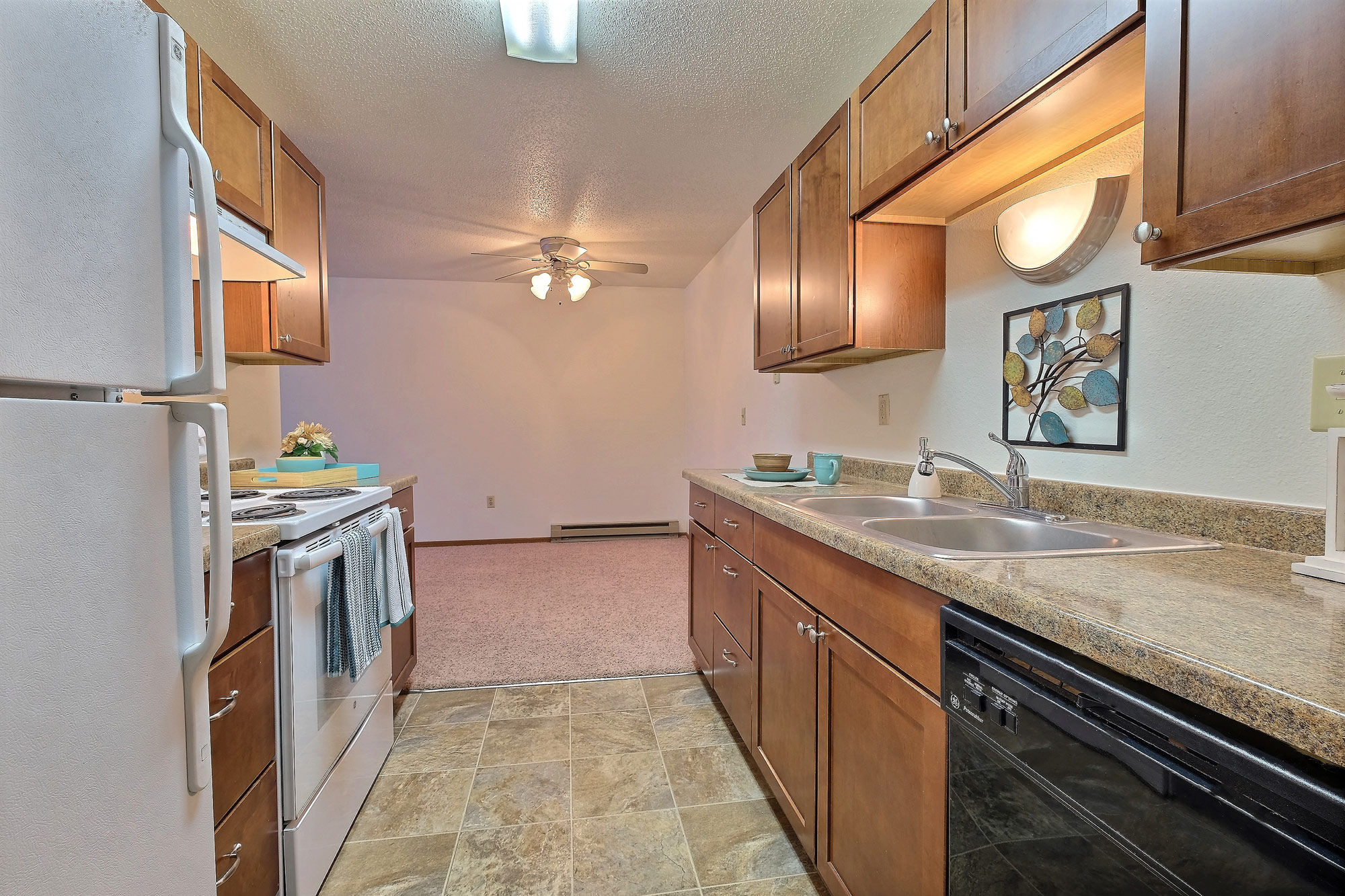 a kitchen with white appliances and wooden cabinets. Fargo, ND Village West Apartments