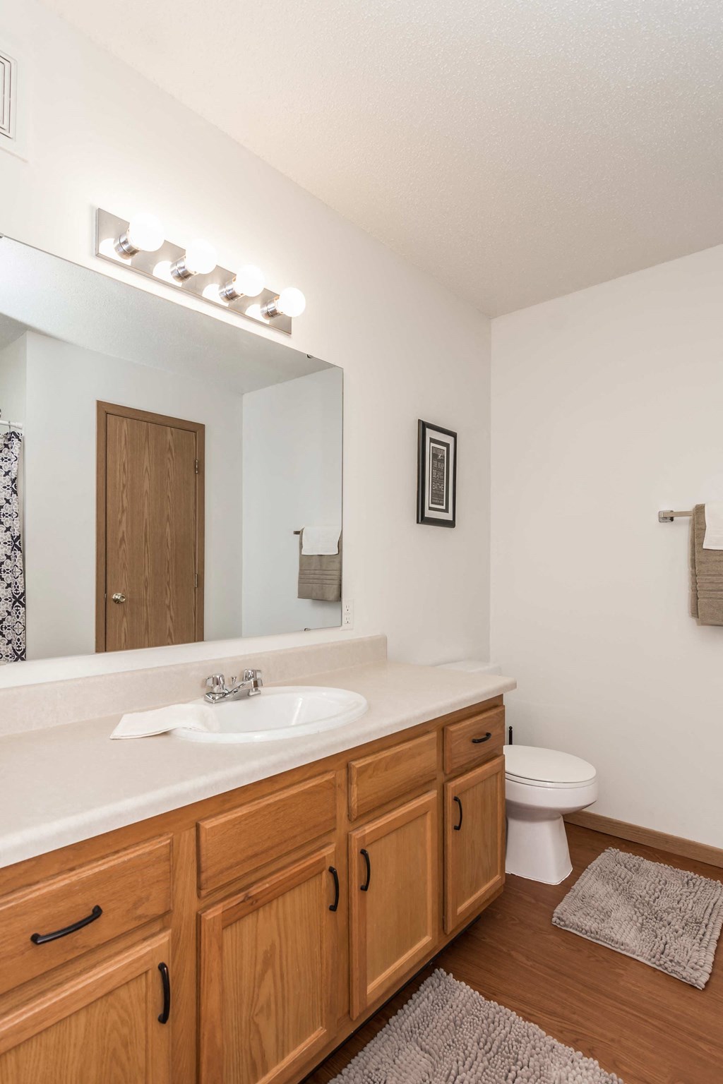 Grand Forks, ND Vista Apartments. a bathroom with a toilet sink and mirror