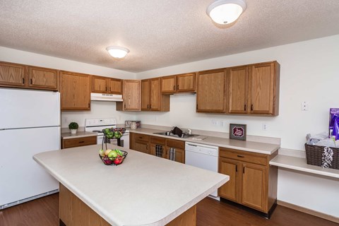 Grand Forks, ND Vista Apartments. a kitchen with a large island with a bowl of fruit on it