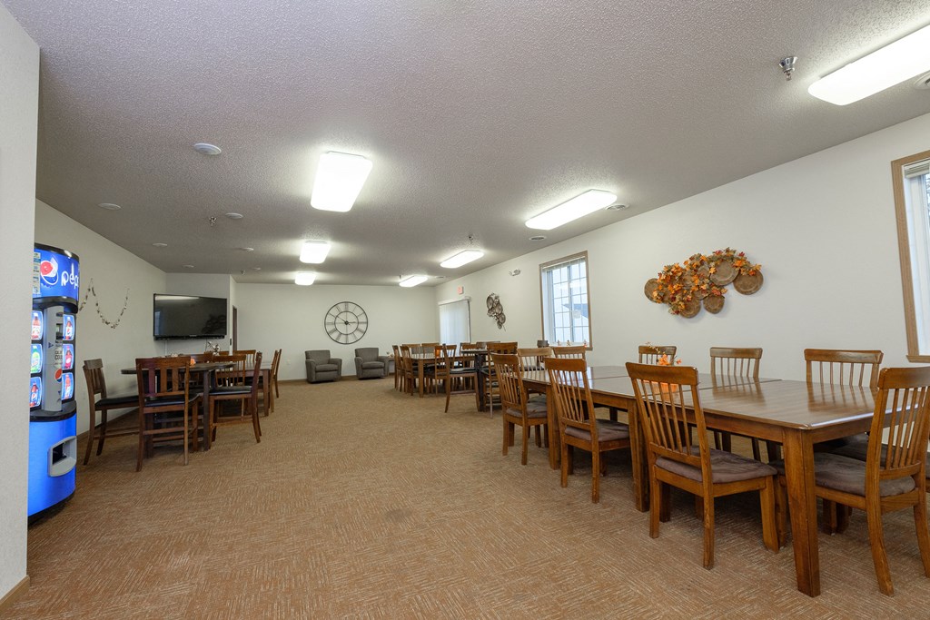 a dining room with tables and chairs and a water cooler. Fargo, ND North Sky Apartments