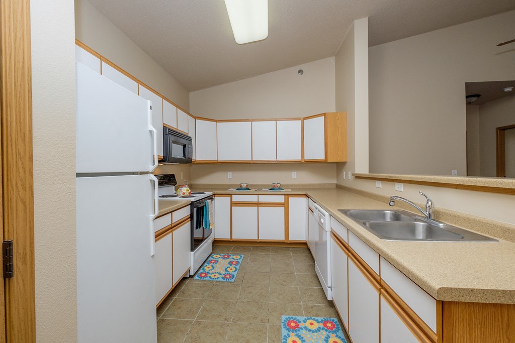 Akitchen with white cabinets and a sink and a refrigerator. West Fargo, ND West Lake Apartments.