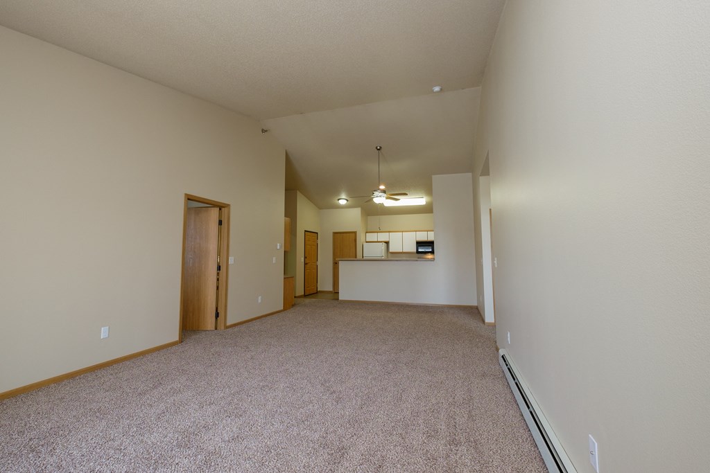A spacious living room with carpet and a kitchen