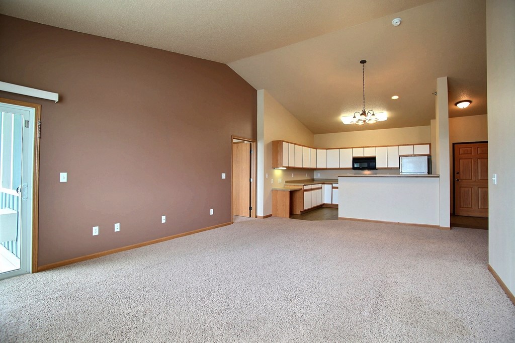 A living room with a kitchen in the background. West Fargo, ND West Lake Apartments.