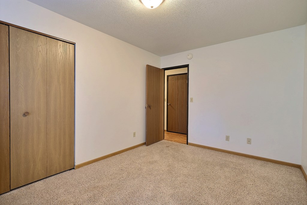 a bedroom with a door to the hallway and a closet. Fargo, ND Westcourt Apartments