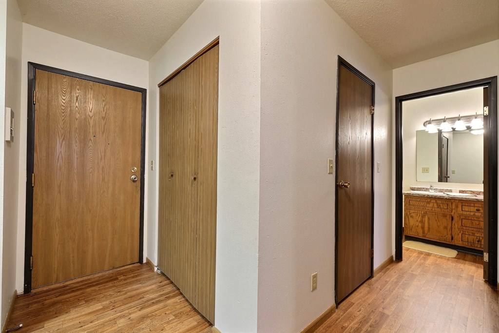 the entryway to a bedroom with two closets and a bathroom with a mirror. Fargo, ND Westcourt Apartments
