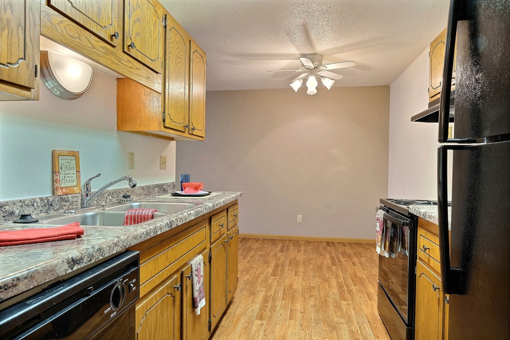 a kitchen with wooden cabinets and a sink and a refrigerator. Fargo, ND Westcourt Apartments