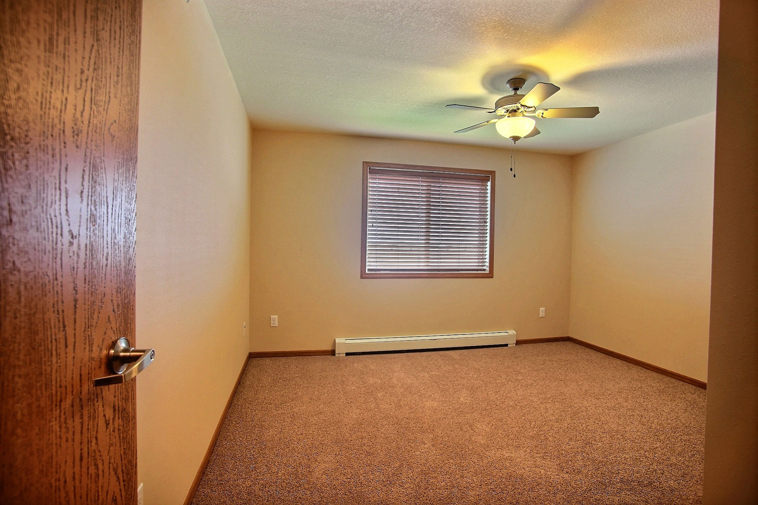 a bedroom with a window and a carpeted floor. Fargo, ND Wolf Creek Apartments