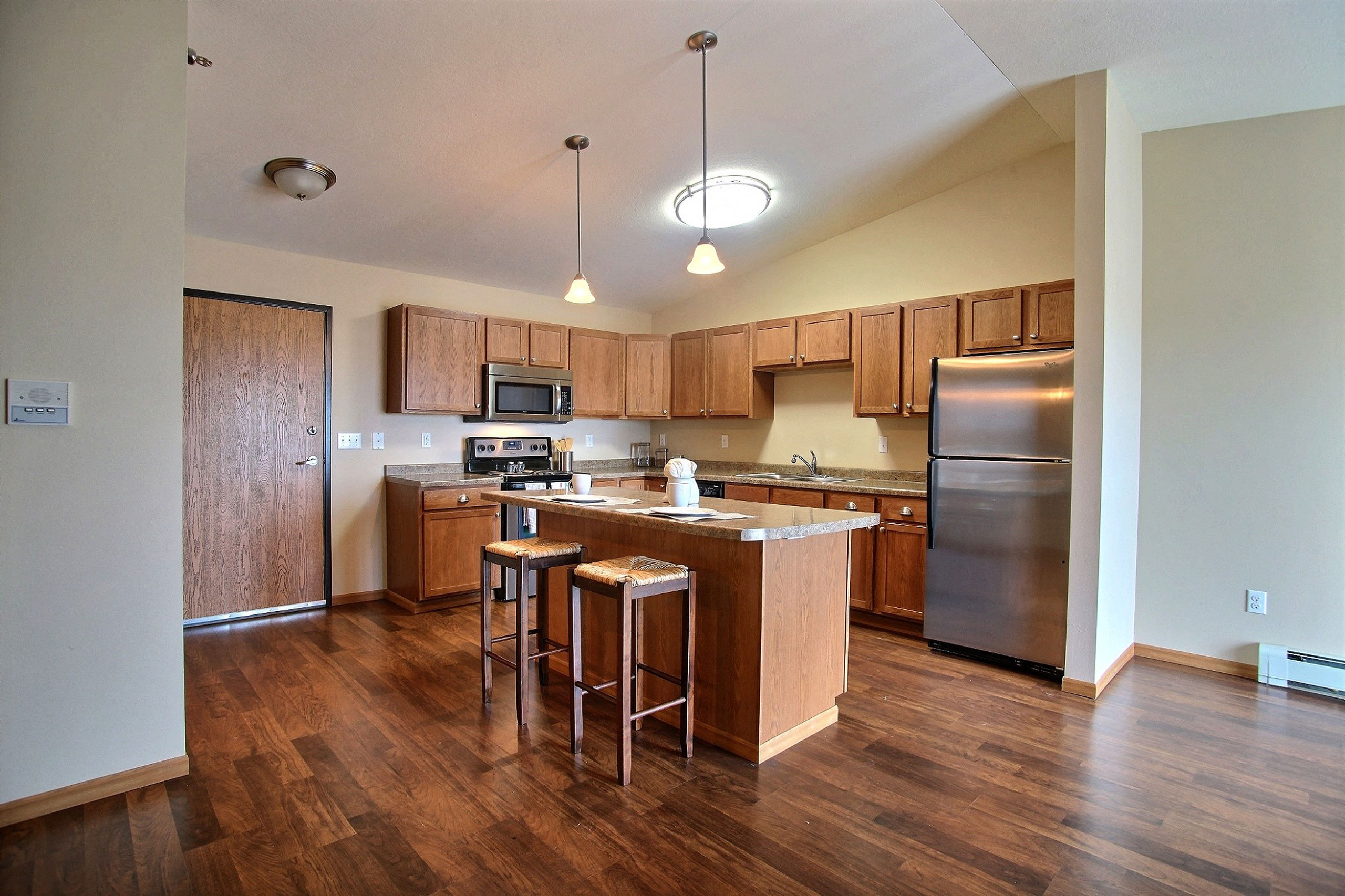 a kitchen with stainless steel appliances and wooden cabinets.Fargo, ND Wolf Creek Apartments